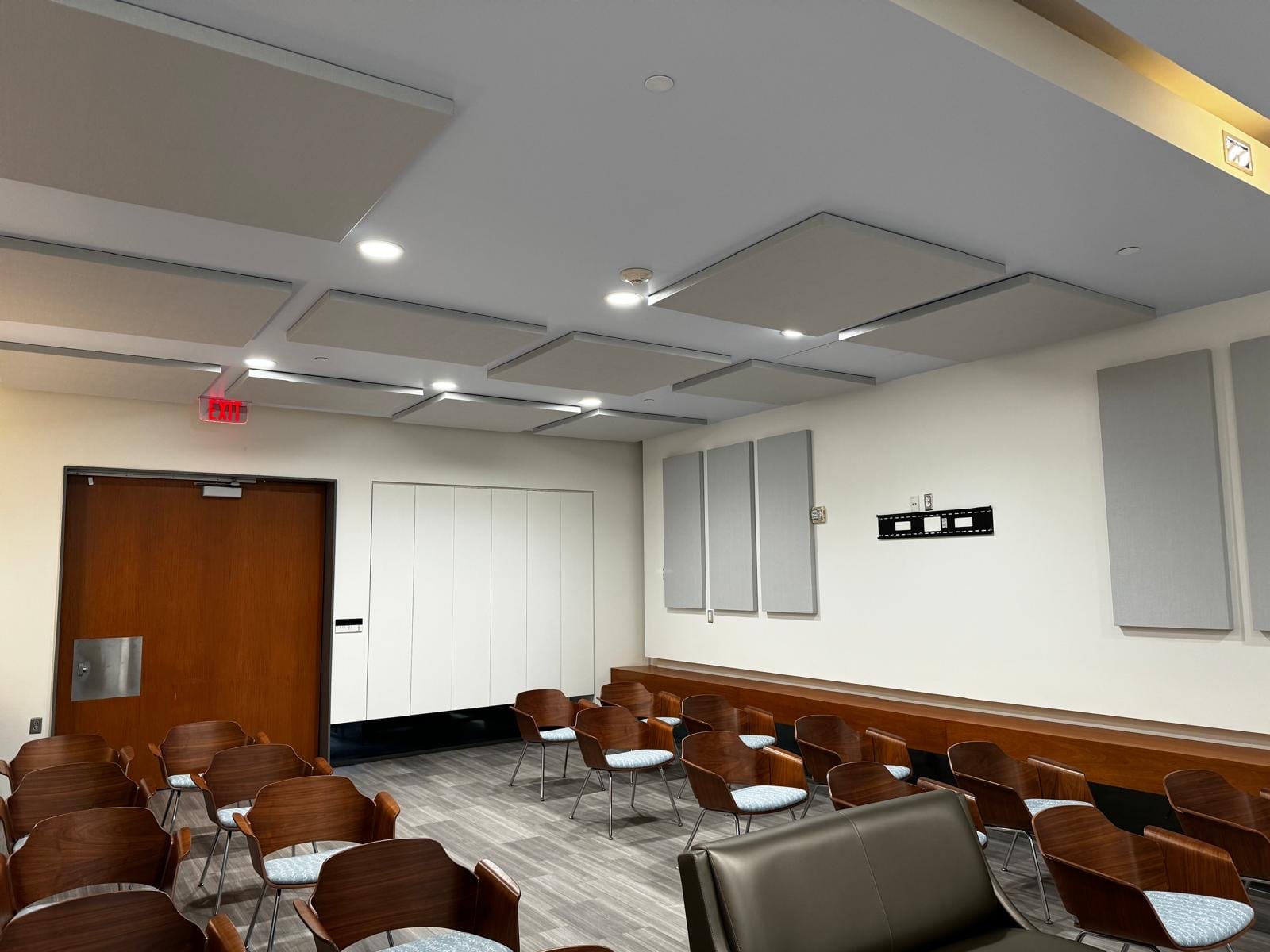 Grey acoustic ceiling clouds and wall panels above seating