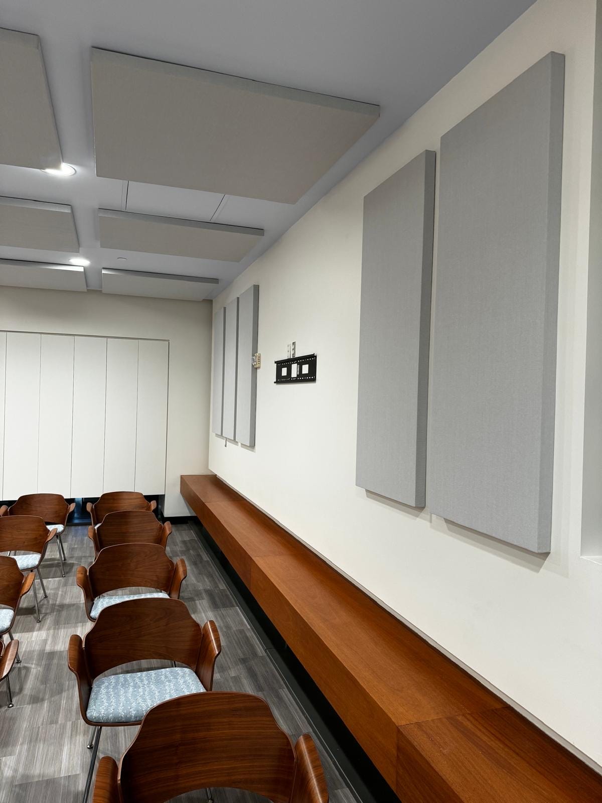 Angled grey acoustic ceiling clouds and wall panels in a meeting room