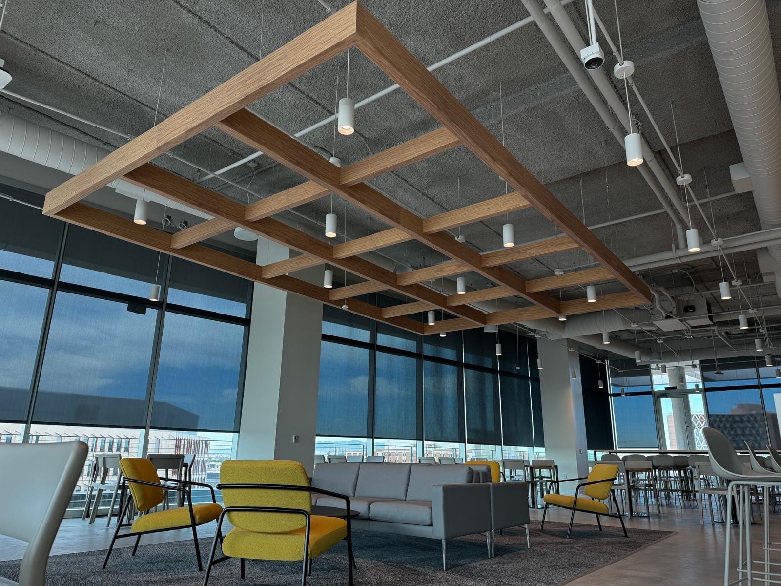 Wood-slat acoustic ceiling and wall treatment in a warm office lounge