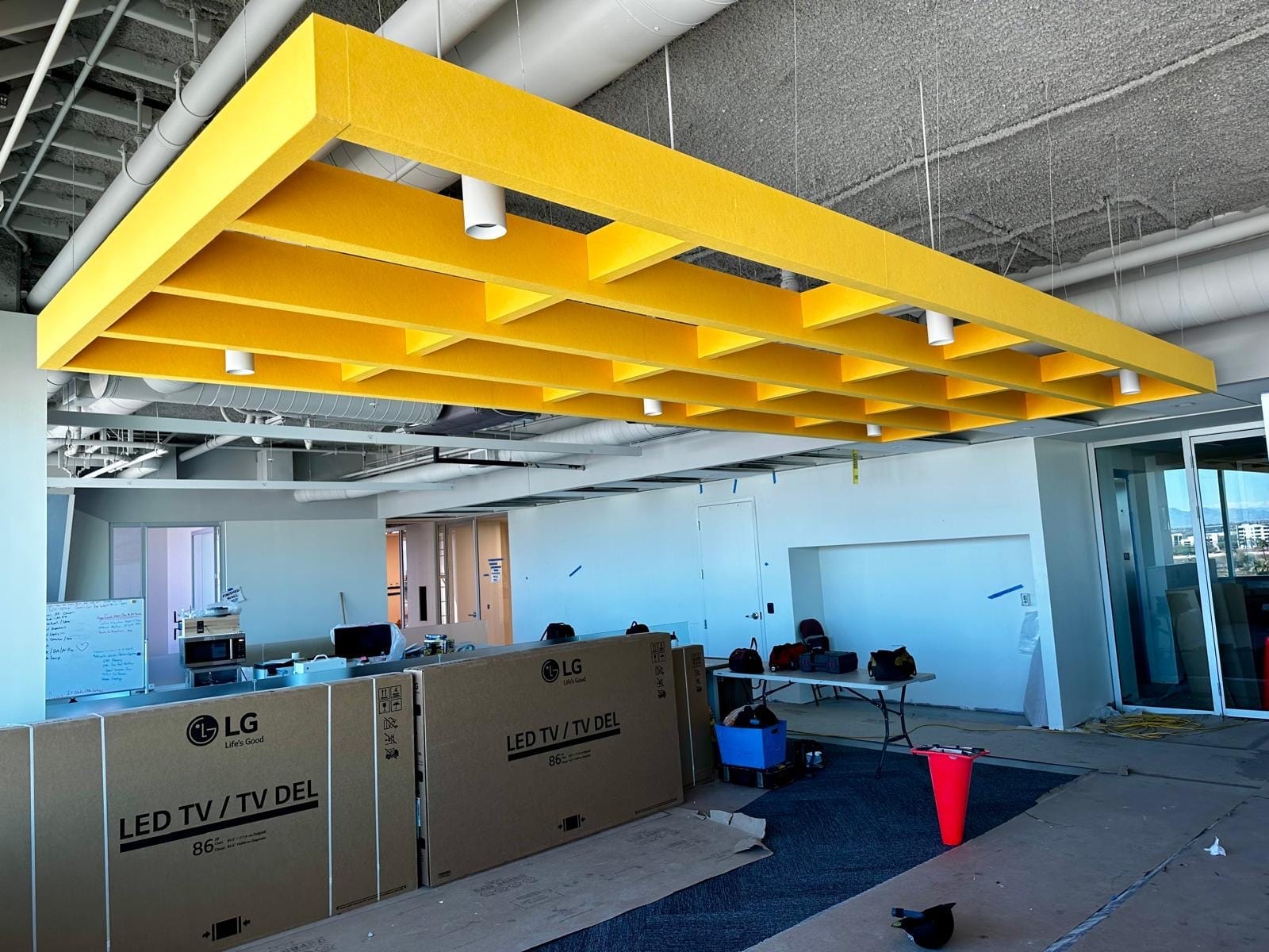 Large yellow acoustic baffle cloud suspended over an open office