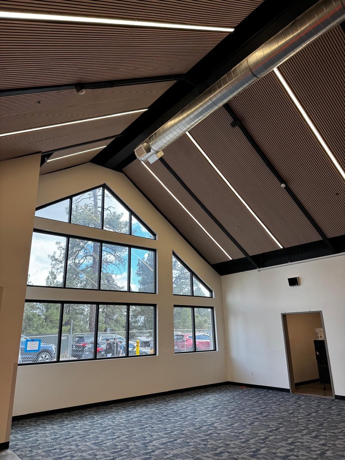 Angled view of a wood-slat acoustic ceiling in a mountain-school multipurpose room