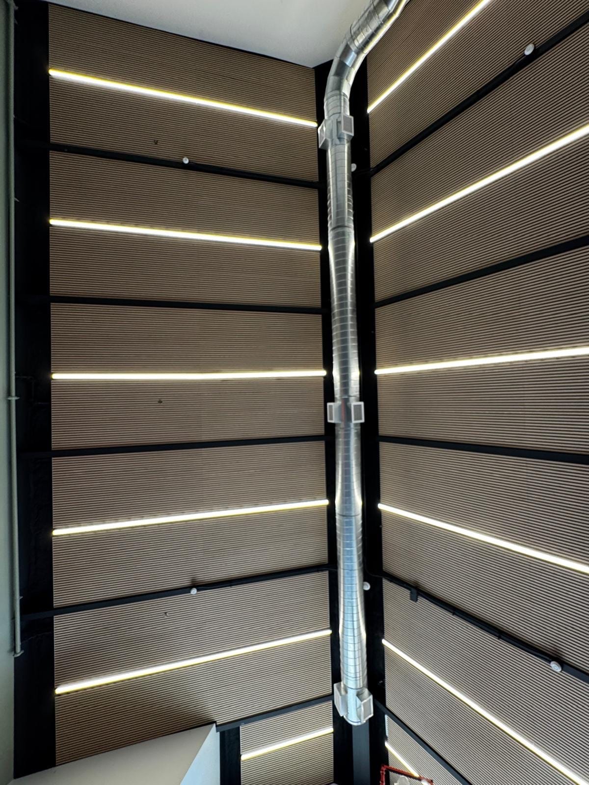 Wood-slat acoustic wall panels lining a tall stairwell