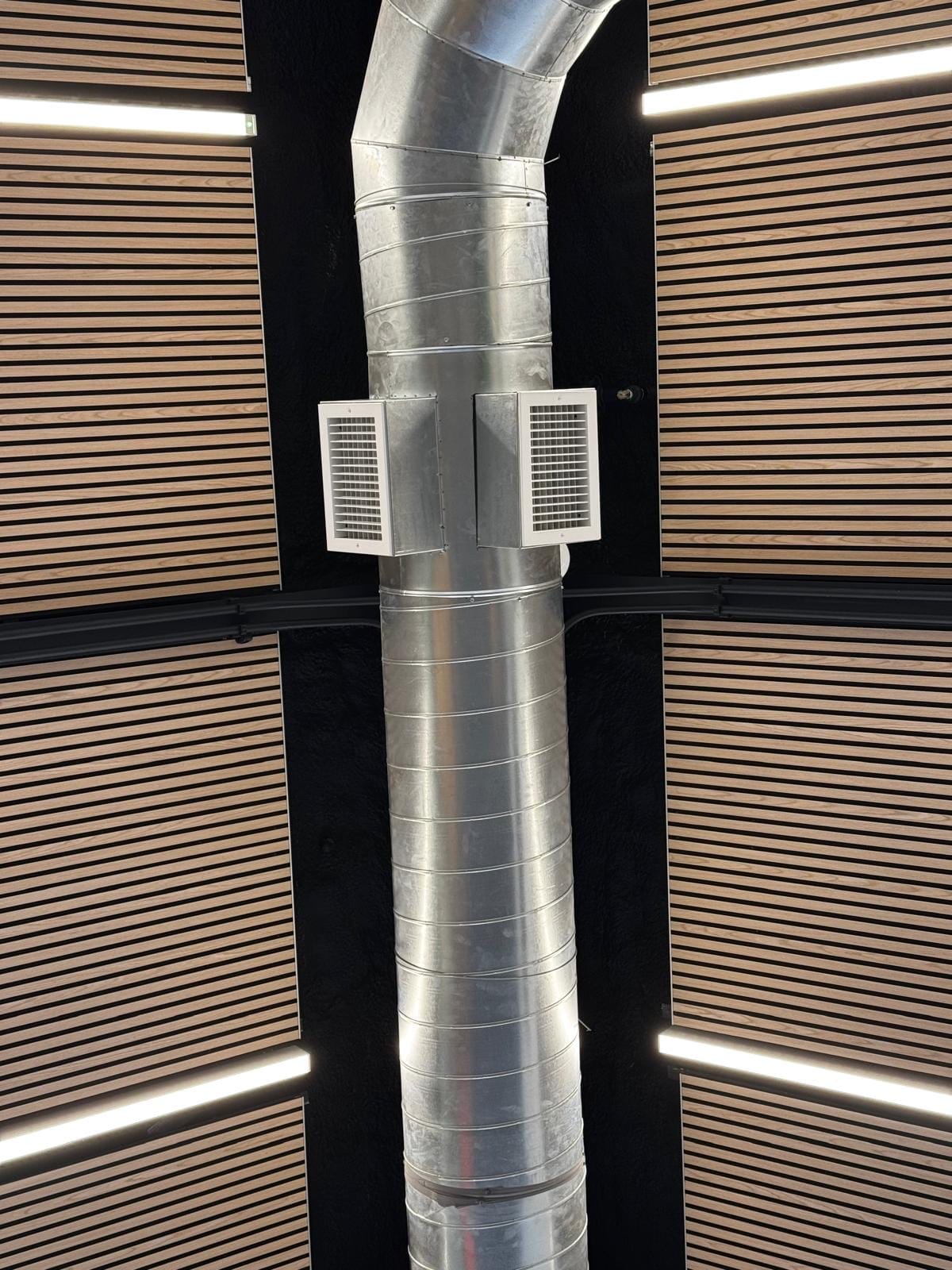 Wood-slat acoustic wall treatment around exposed ductwork